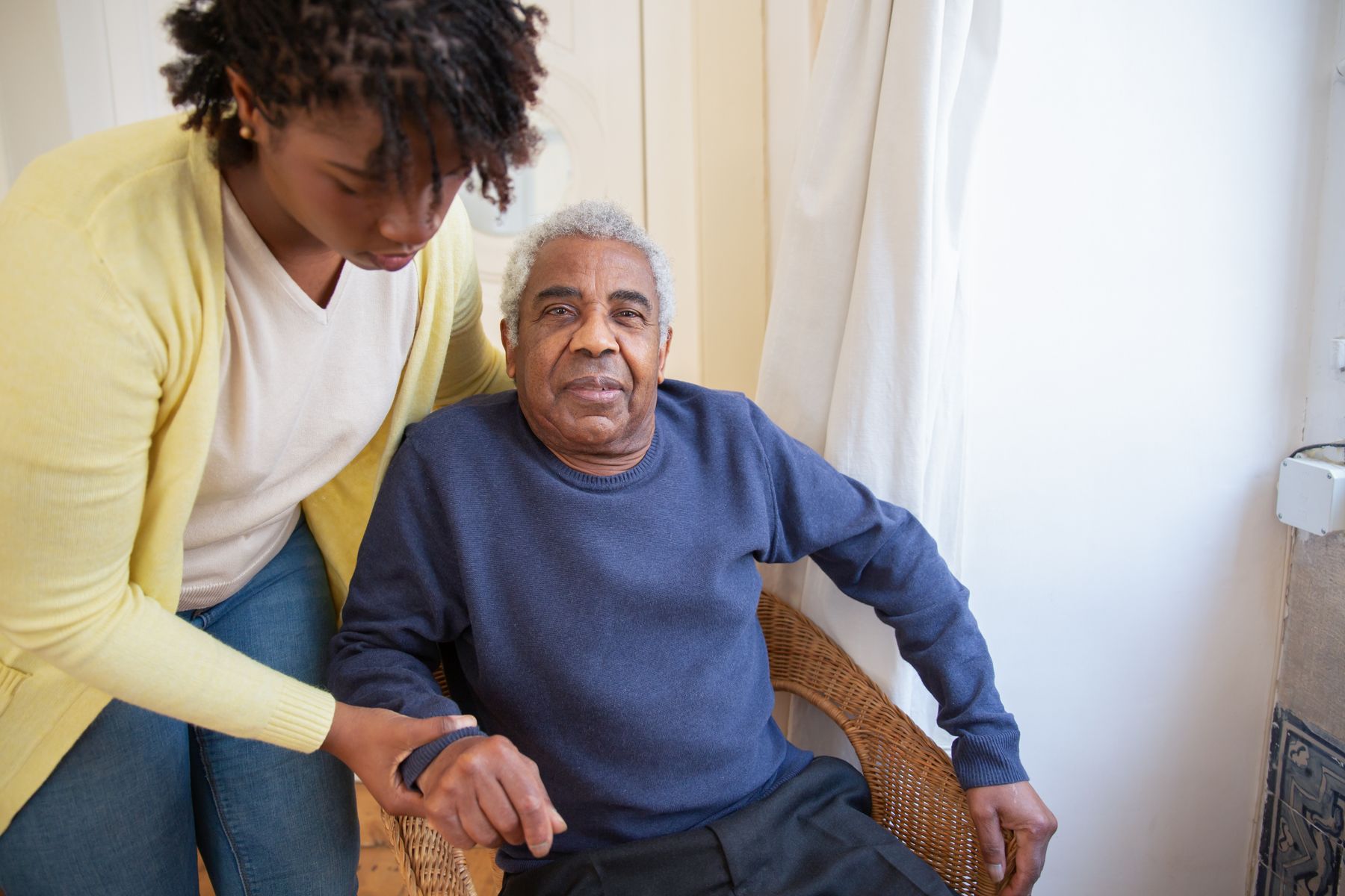 Caregiver attentively assisting an older man at home