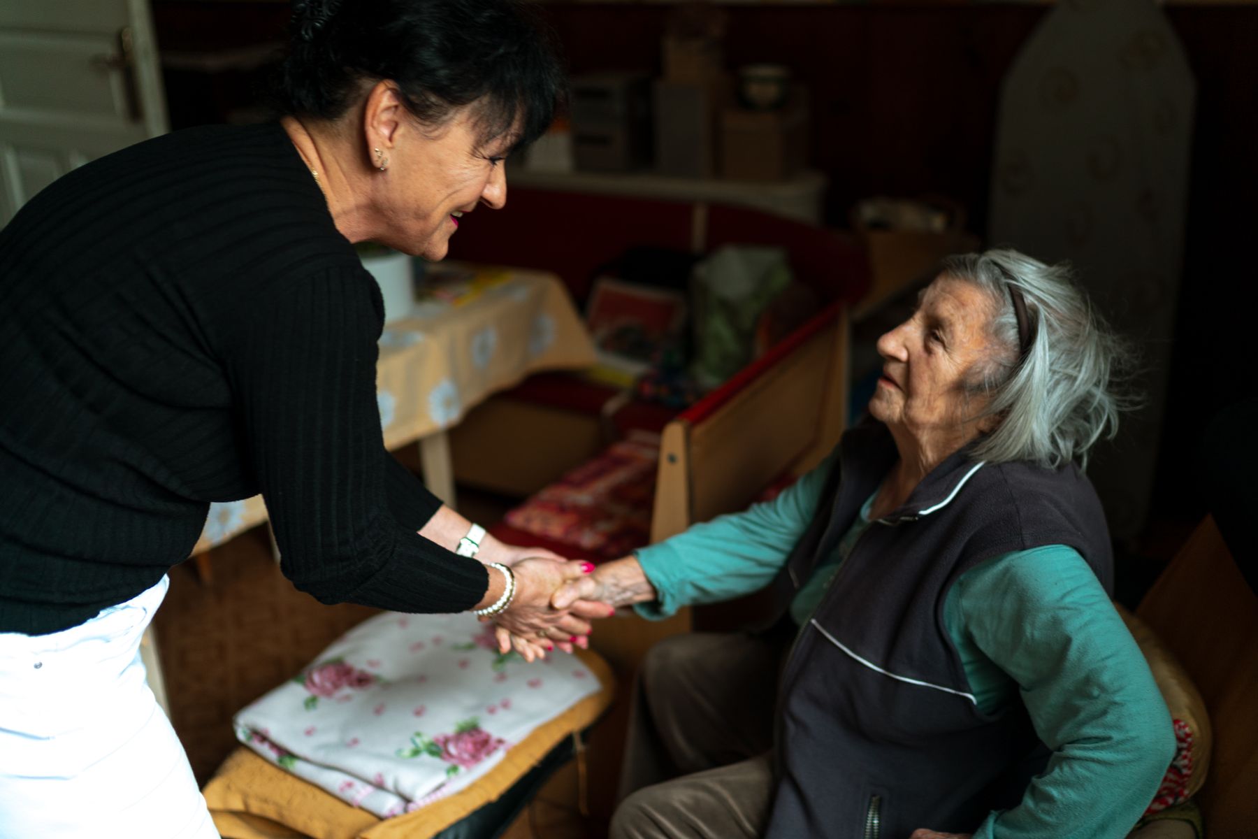 A health aide warmly supporting an elderly woman at home
